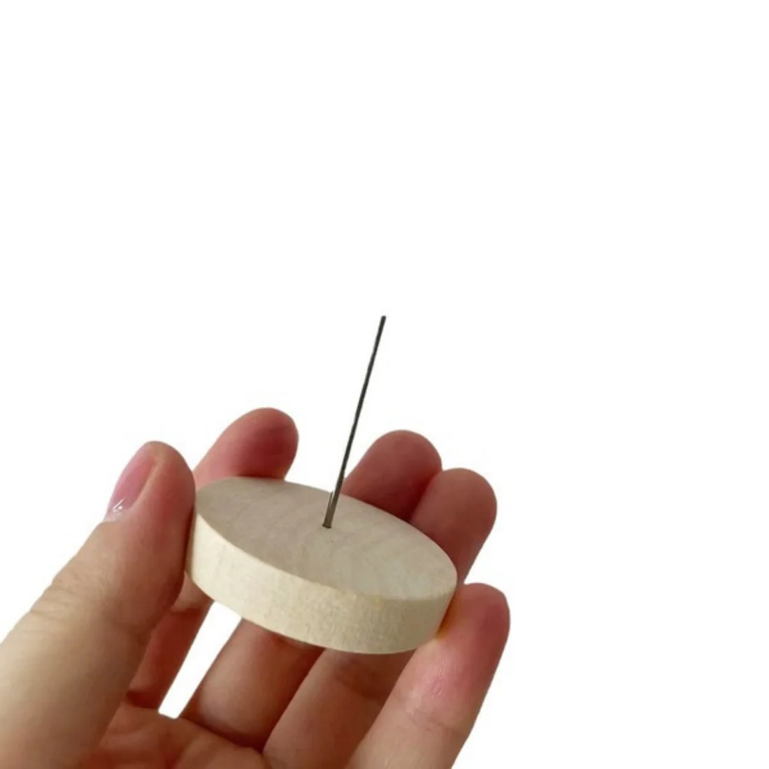 The wooden needle base, held in a hand to show its size